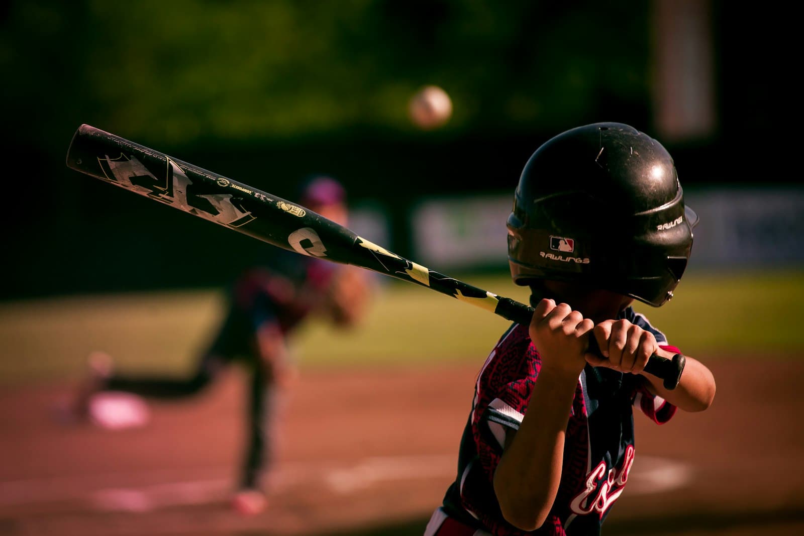 Young baseball player at bat under evening light